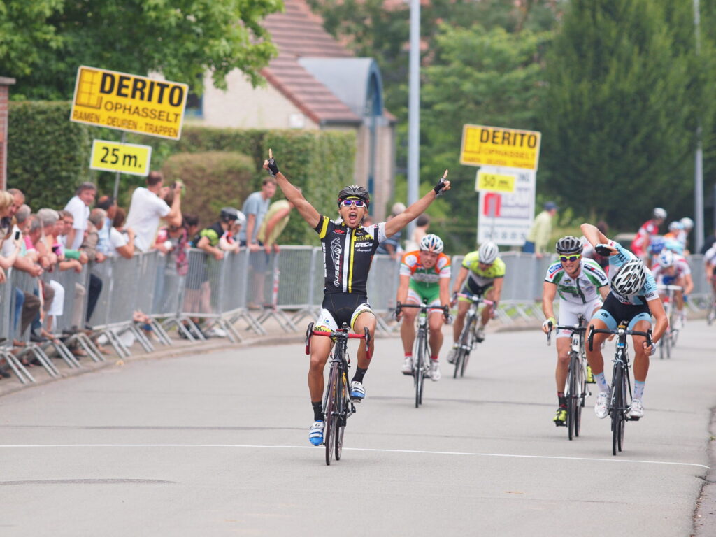 ロードレースでゴールし両手を上げて勝利を喜ぶ自転車選手